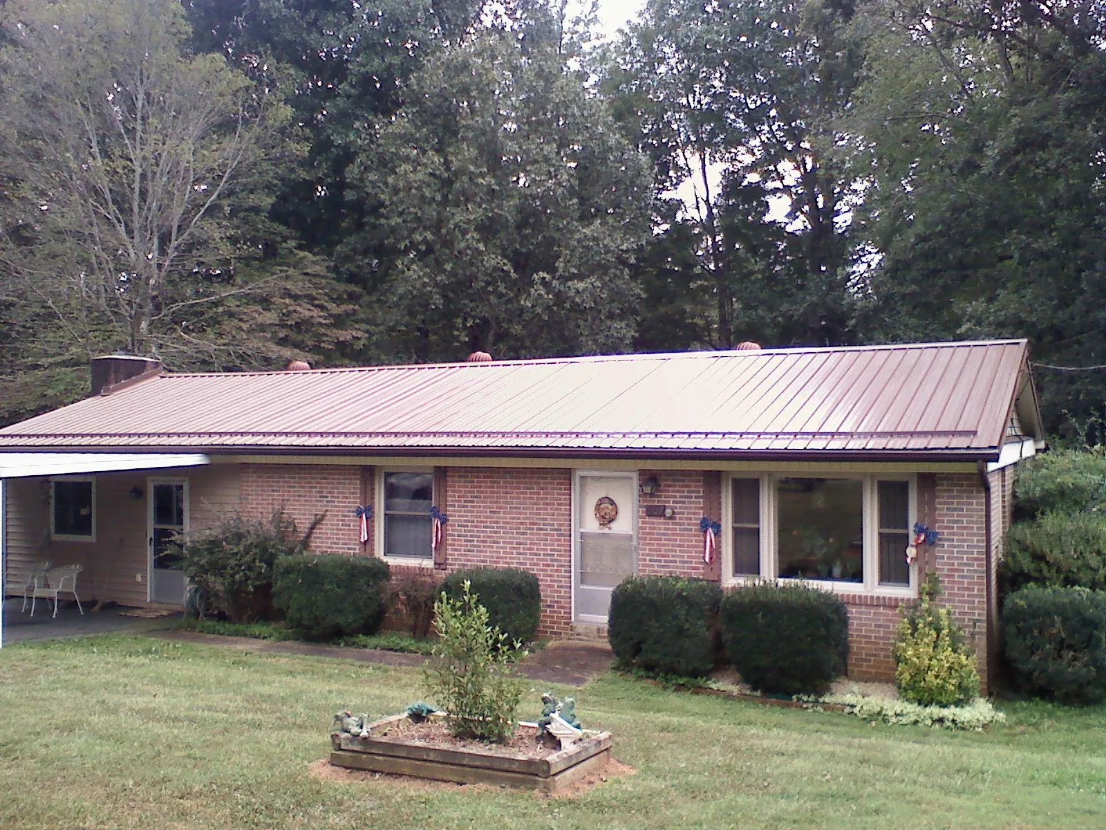 Bronze metal roof on a brick ranch home with a carport in Rogers