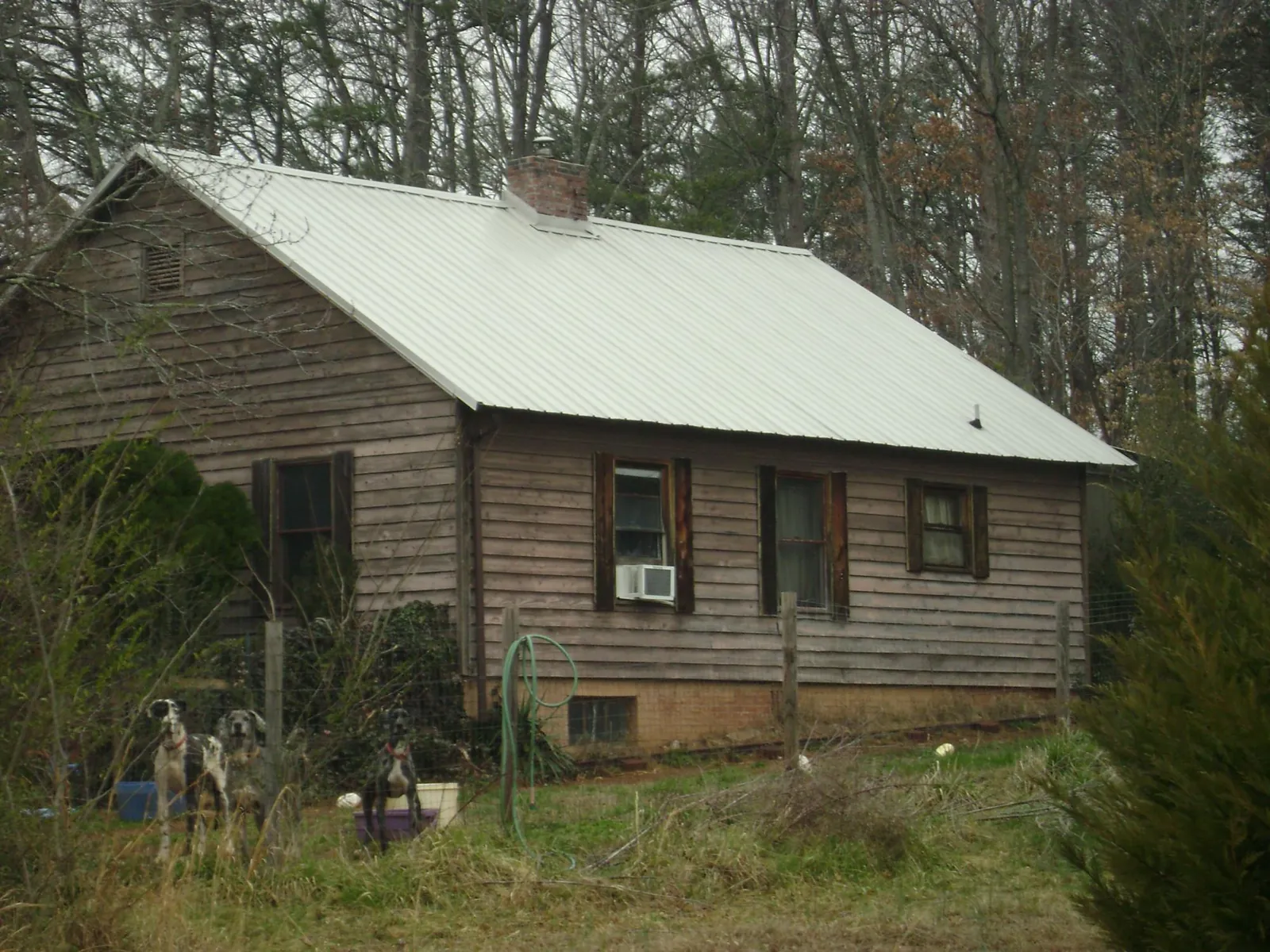 White metal roof on an old wood sided farmhouse, from a Metal Roof Installation job in Rogers